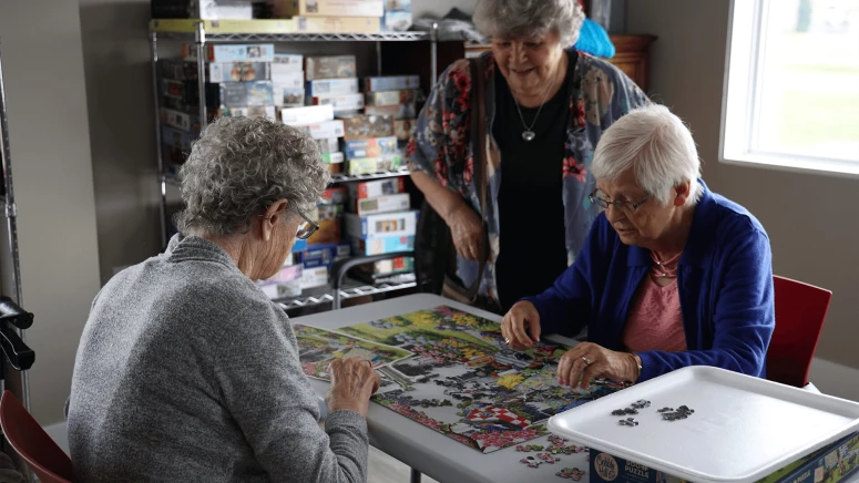 Three elderly women solving Jigsaw puzzle at Westsyde's residence